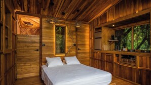 Een houten slaapkamer met een bed, een raam en een ingebouwde kitchenette.