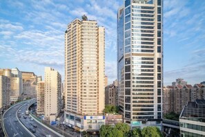 A high-rise building with multiple floors, surrounded by other tall buildings, and a busy road with vehicles. - Citadines Apart Hotel (Shanghai Yan'an West Road) (Shanghai)