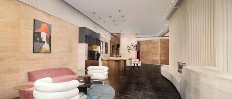 A modern hotel lobby with a curved marble floor, a reception desk, and contemporary seating.