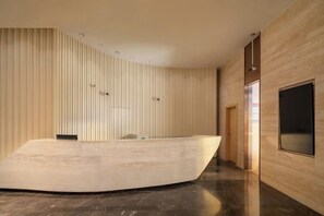 A modern interior with a curved reception desk, wooden panel walls, and a large window.