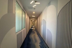 Ein Korridor mit geradem Gang, eingelassener Beleuchtung und einer Wand mit Muster rechts.