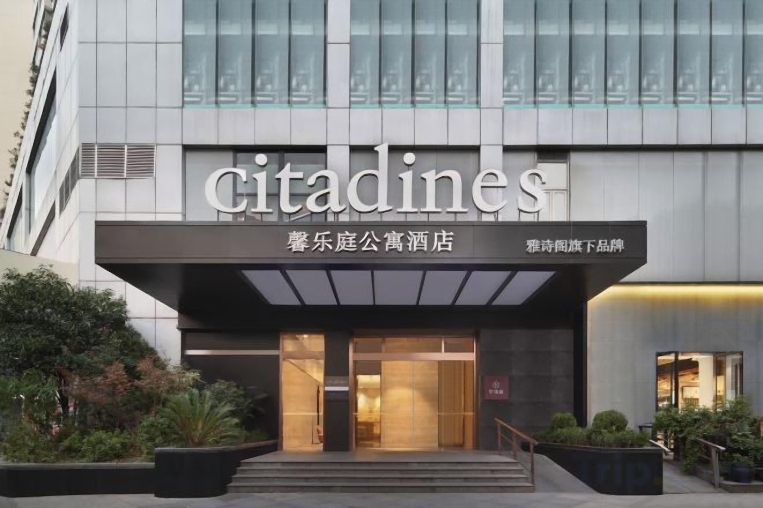 Um edifício moderno com a placa 'citadines', fachada de vidro e entrada bem iluminada.