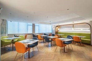 A modern dining area with tables and chairs, large windows, and a green seating area. - Citadines Apart Hotel (Shanghai Yan'an West Road) (Shanghai)