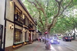 Ruas arborizadas com edifícios, um ônibus e carros.