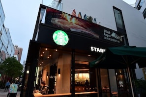 A Starbucks store with a large sign and a green awning.