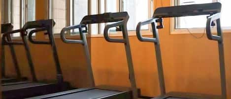 A row of treadmills in a gym with a window in the background.