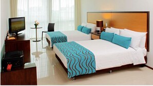 A hotel room with two beds, a TV, a desk, and a small table with a flower. - Hotel Tiburon (Guadalajara)