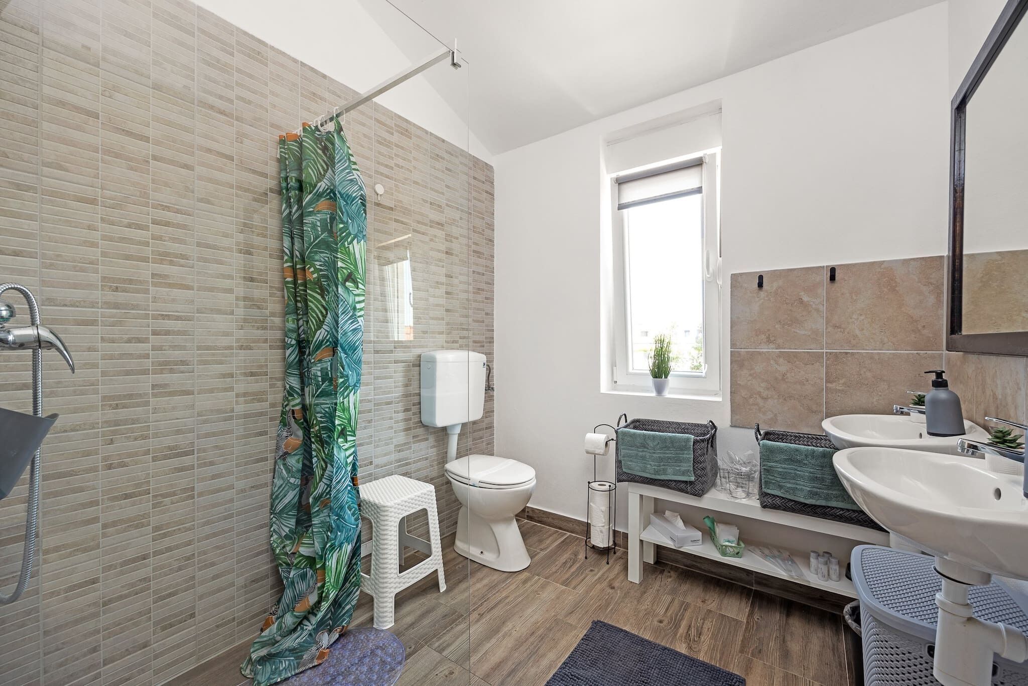Een moderne badkamer met douche, toilet en wastafel.