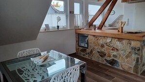 A modern kitchen with a stone backsplash, wooden beams, and a glass dining table. - The Mediterrean apartment in the Wine Town Hessigheim, modern and stylish. (Hessigheim)