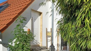 A house with a red-tiled roof, a white exterior, and a small front yard with steps leading to the entrance. - The Mediterrean apartment in the Wine Town Hessigheim, modern and stylish. (Hessigheim)