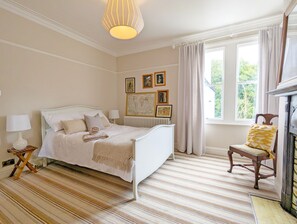 Une chambre bien rangée, avec un lit, une chaise et une cheminée.