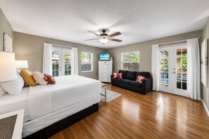 Une chambre à coucher comprenant un lit, une télévision, un ventilateur de plafond, une commode et un canapé.