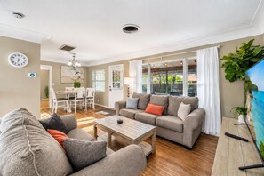 Ein Wohnzimmer mit einer Couch, einem Couchtisch und einem Fernseher, der eine Strandansicht zeigt.