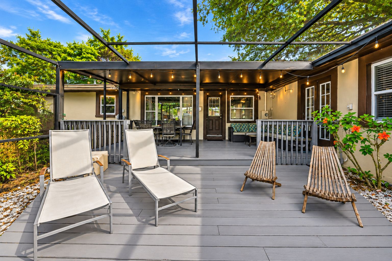 An outdoor deck with seating, a covered area, and a building in the background.