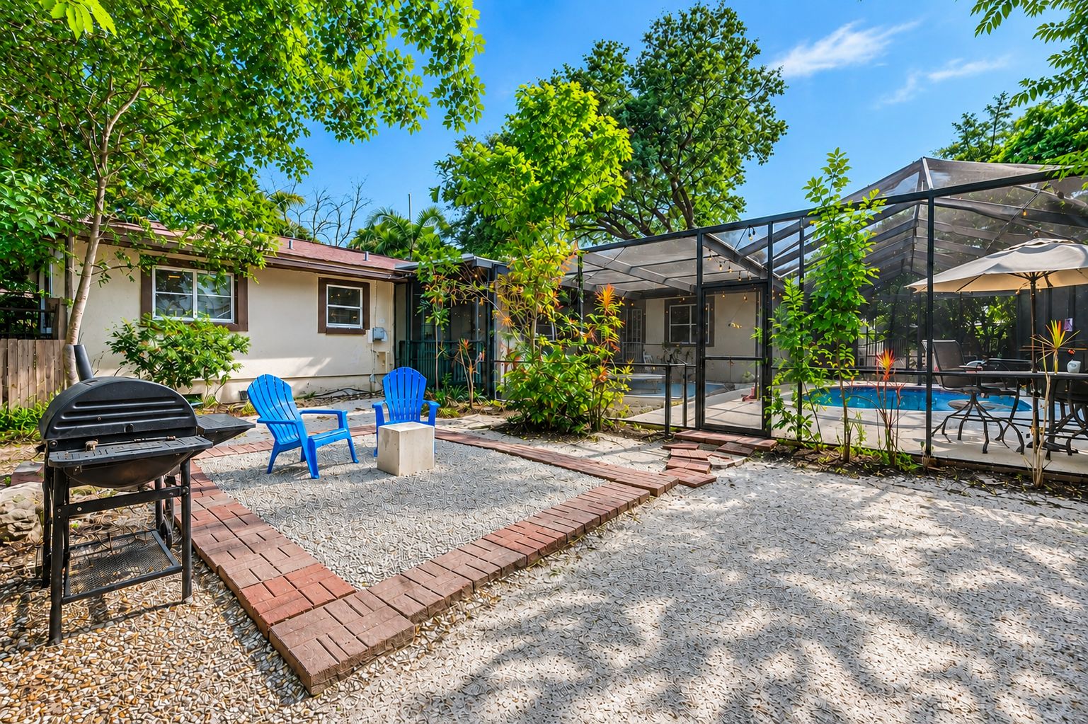 A backyard with a barbecue grill, blue chairs, a pool, and a covered patio area.
