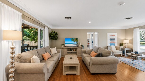 A living room with two sofas, a coffee table, a TV, and a bookshelf. - Cozy Clearwater Pool Home Near Beaches! (Clearwater)