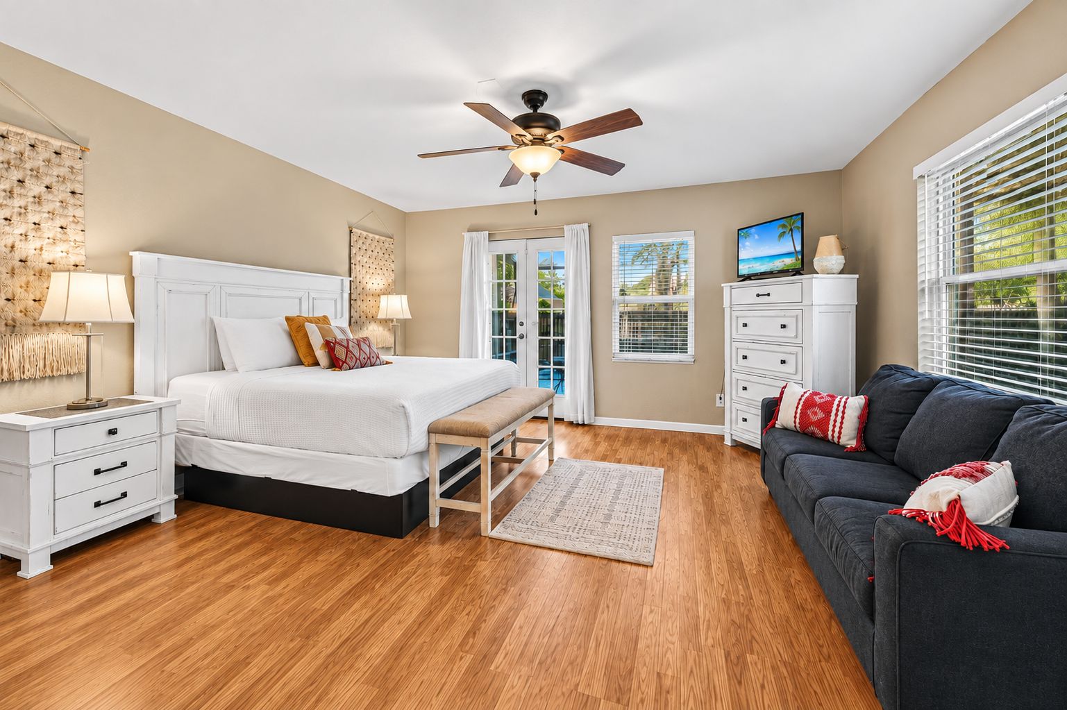 A bedroom with a bed, nightstand, dresser, and a dark-colored sofa.