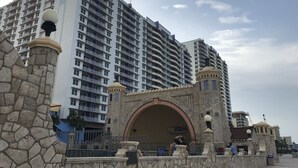 A high-rise hotel with multiple balconies and a stone archway entrance.