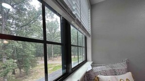 A room with a large window, a bench with patterned cushions, and a pillow with the word "hello" embroidered on it. - Vacation Farmhouse (Lufkin)