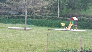 A playground with a swing set and a slide, surrounded by a grassy area and trees.
