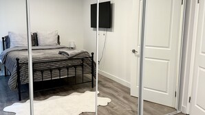 A bedroom with a bed, a mirror, a television, and a wardrobe.