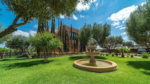 A well-maintained garden with a central fountain, surrounded by lush green grass and trees. - Villa Chems (Marrakech)
