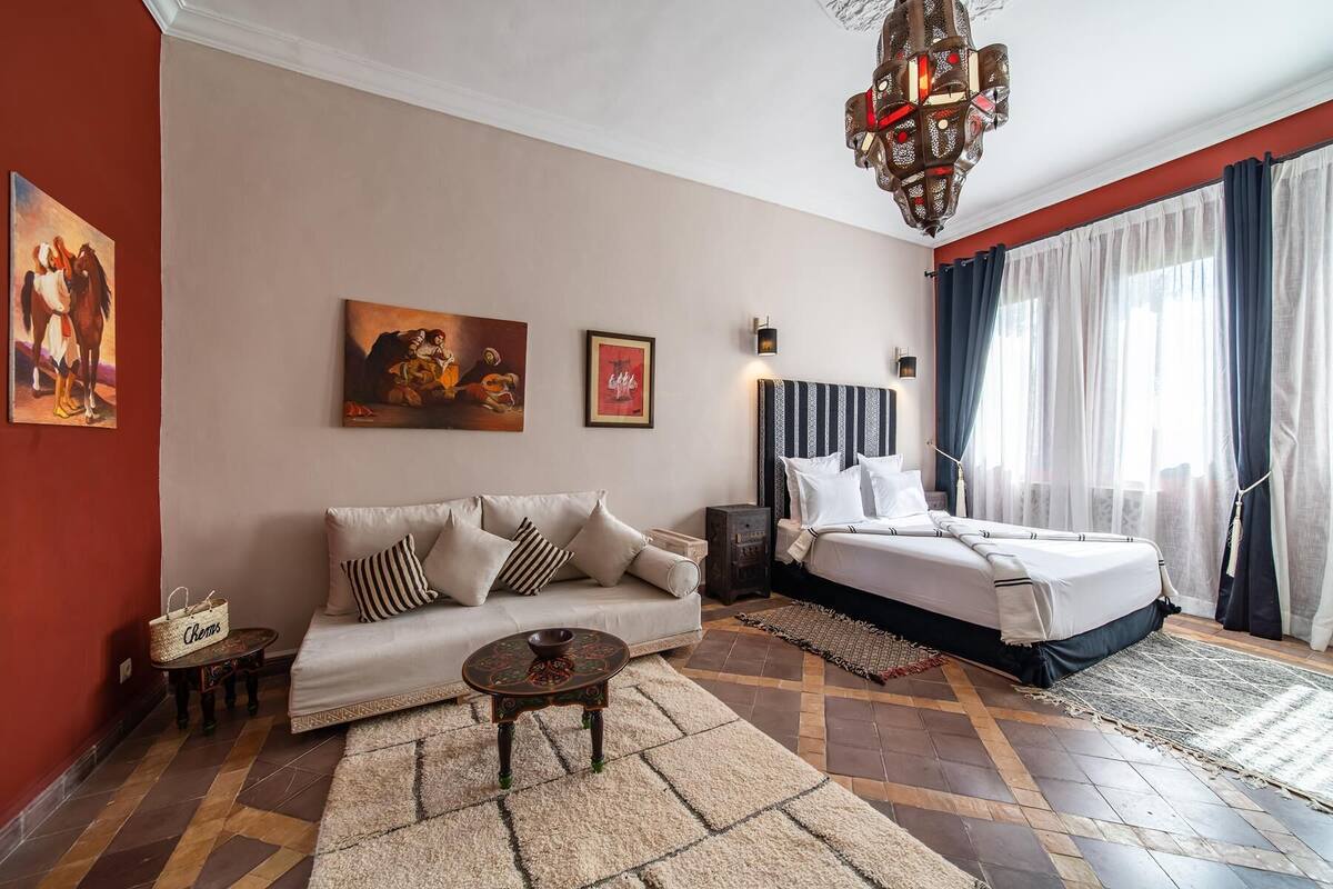 Habitación de hotel con sofá, cama, una mesita y obras de arte en las paredes.