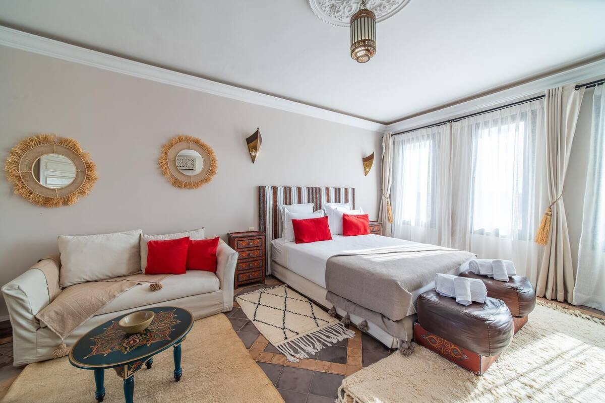 Una habitación de hotel con cama, sofá, una mesita y espejos decorativos en la pared.