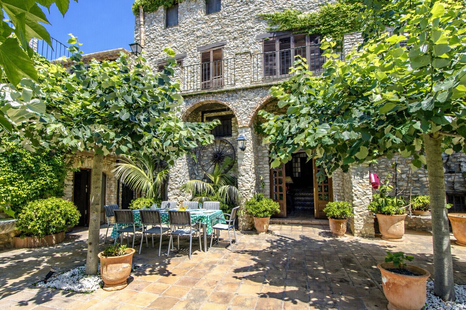 Un edificio de piedra con patio, mesas al aire libre y macetas con plantas.