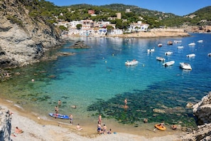 Une ville côtière aux eaux cristallines, où l’on peut voir des bateaux et des gens sur la plage.
