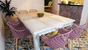 Un'area pranzo con un tavolo di legno, sei sedie viola e una ciotola di frutta.