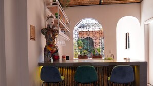 Angolo bar con tre sedie, una scultura decorativa e una finestra che si affaccia su un giardino ad arco.