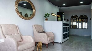 A reception area with two beige armchairs, a white cabinet, a gold-framed mirror, and a small golden lion statue. - İdeal Butik Otel (Arnavutköy)