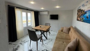 A room with a dining table, chairs, a sofa, a TV mounted on the wall, and a painting. - İdeal Butik Otel (Arnavutköy)