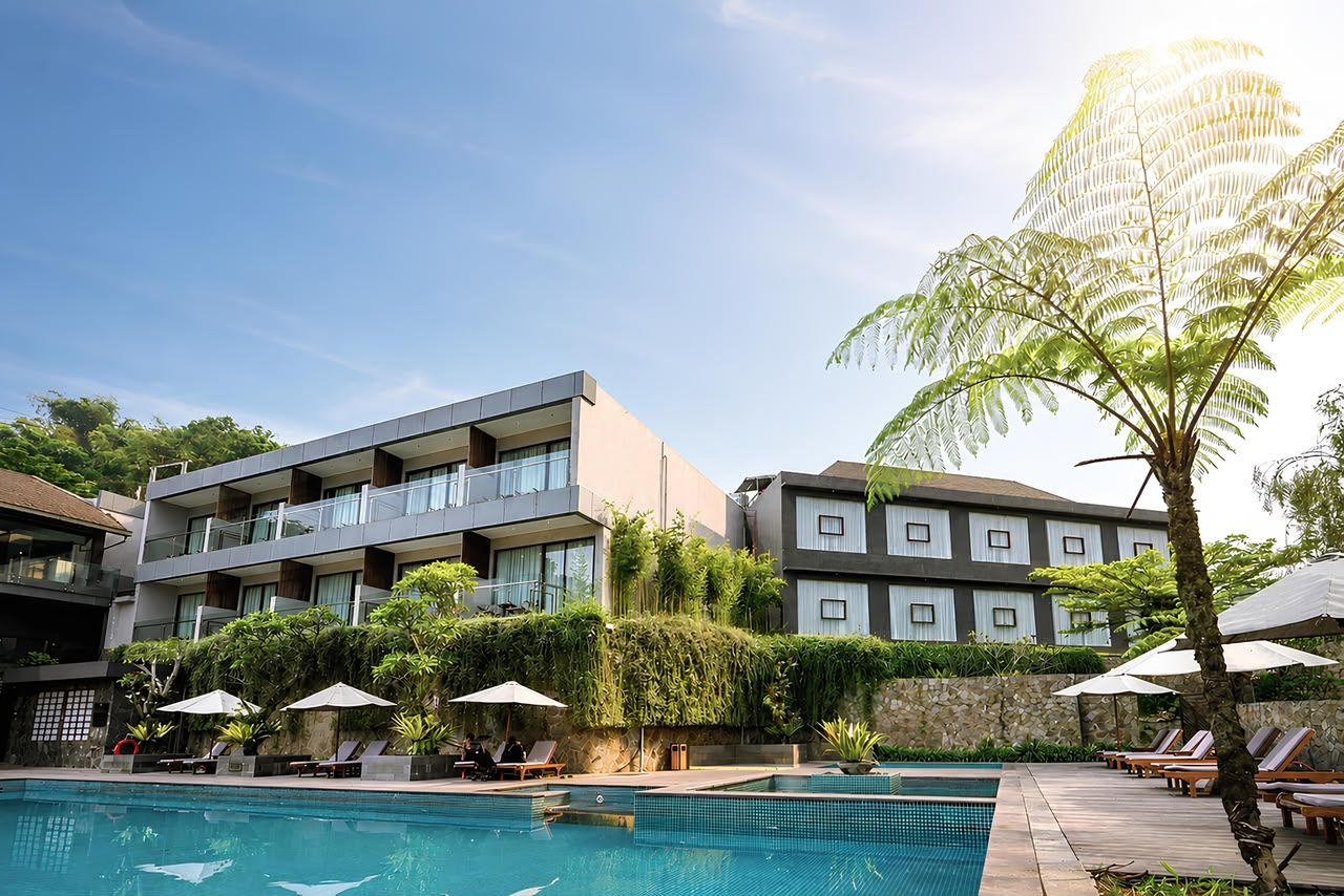 A hotel with a swimming pool, multiple balconies, and outdoor seating areas.