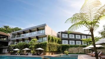 A hotel with a swimming pool, multiple balconies, and outdoor seating areas.