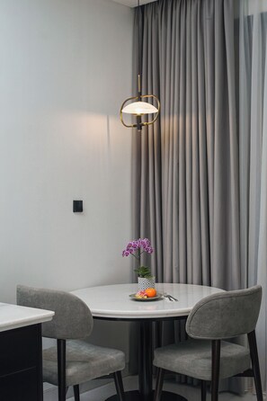 Een moderne eethoek met een ronde tafel, twee stoelen, een hanglamp en een potorkidee.