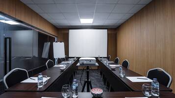 A conference room with a long table, chairs, a projector, and a whiteboard.