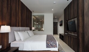 A modern bedroom with a large bed, a TV, and a mirror. - Forest Hills Hotel Ciwidey (Pasirjambu)