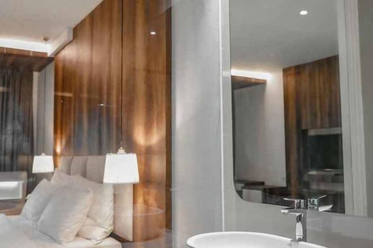 Un bagno moderno con uno specchio grande, un lavandino bianco e una parete rivestita in legno.