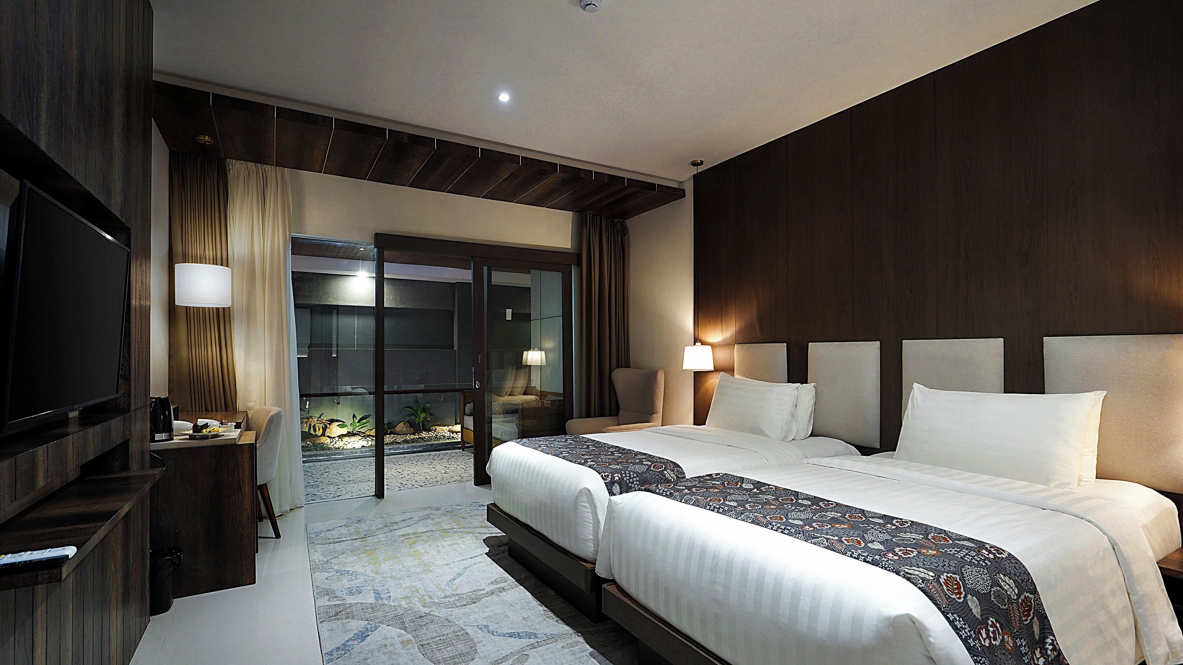 A hotel room with a large bed, a TV, a desk, and a view of a pool.