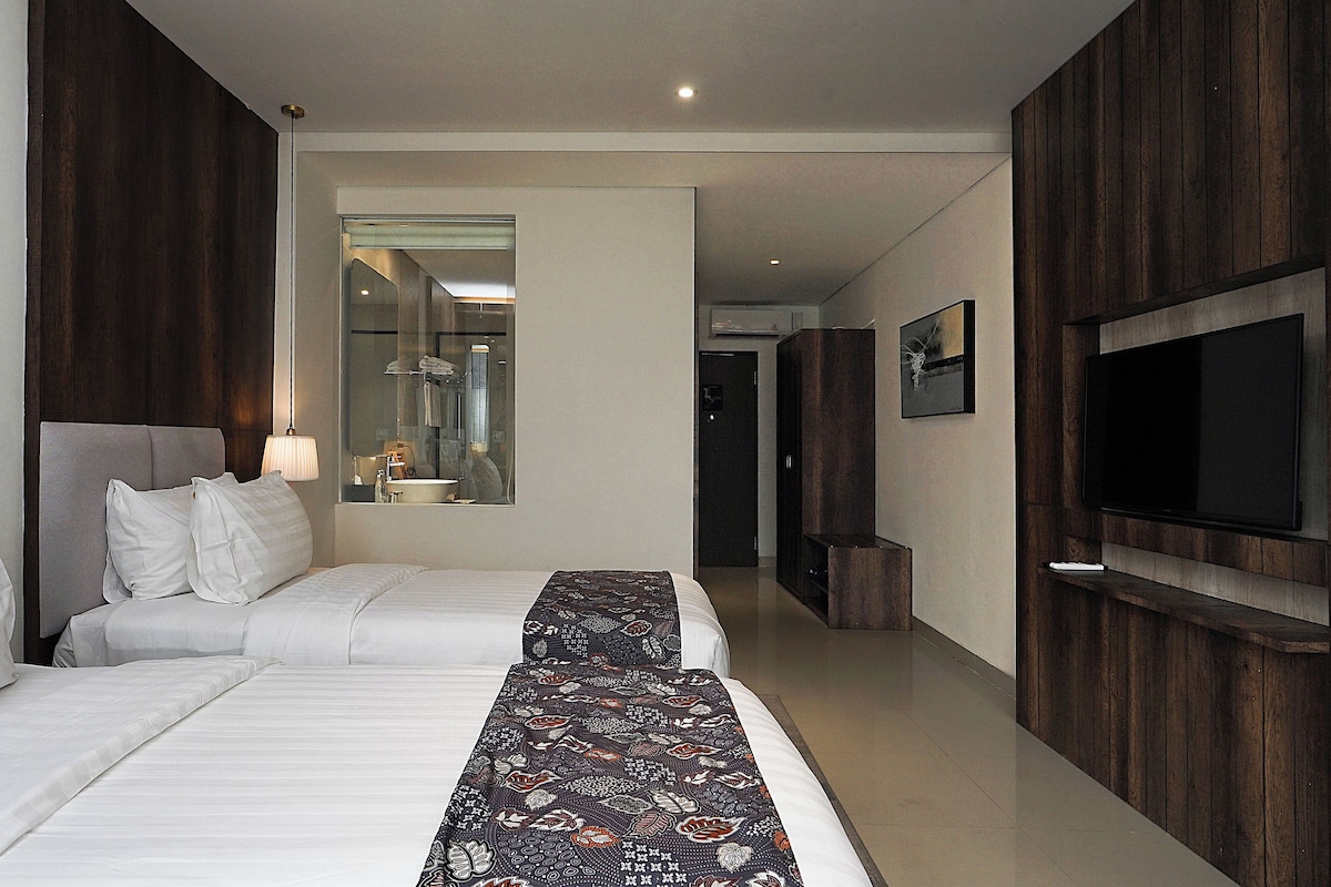 A hotel room with a large bed, a TV mounted on the wall, and a mirror reflecting the room.