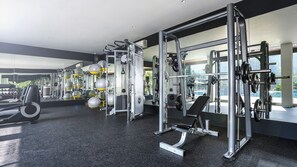 A modern gym with various exercise equipment, large windows, and a black speckled floor. - Forest Hills Hotel Ciwidey (Pasirjambu)