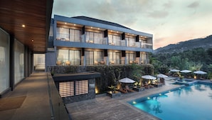 Un hotel moderno con piscina, asientos exteriores y vistas del paisaje circundante.