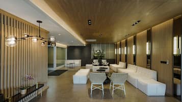 A modern interior with a long reception area, white sofas, a coffee table, and a wooden ceiling.