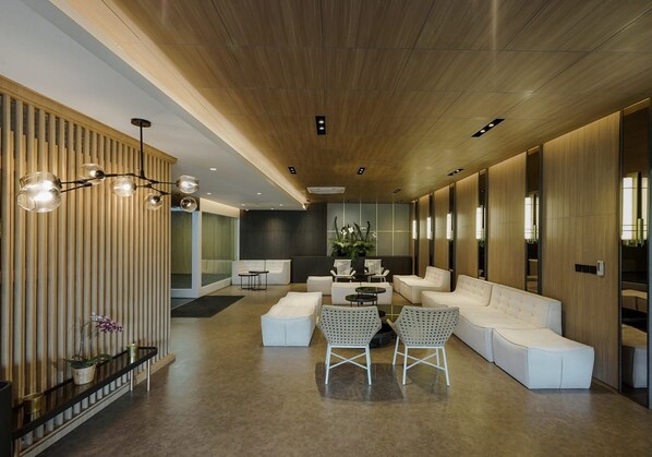 A modern interior with a long reception area, white sofas, a coffee table, and a wooden ceiling. - Forest Hills Hotel Ciwidey (Pasirjambu)