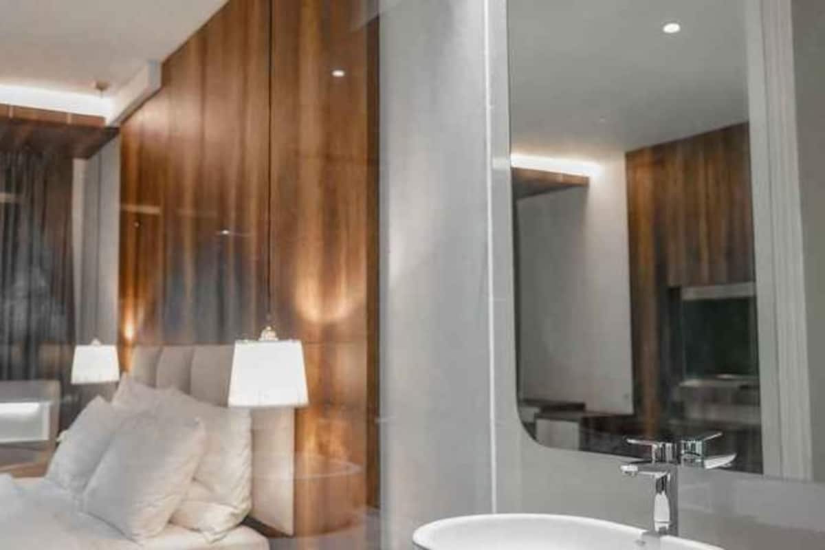 A modern bathroom with a large mirror, a white sink, and a wooden panel wall.
