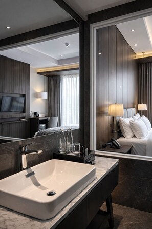 Un baño de hotel moderno con un espejo grande, un lavabo y una tocador.