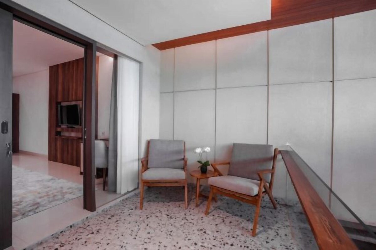 A modern room with two wooden chairs, a small table with a potted plant, and a large window with a view of the outside.