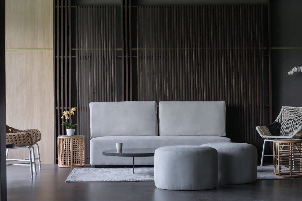 Ein modernes Wohnzimmer mit grauem Sofa, einem runden Couchtisch und einem Korbstuhl.